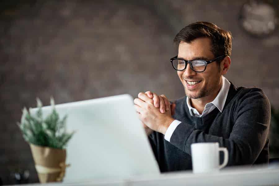 Happy male entrepreneur using laptop while working in the office hotline managerial
